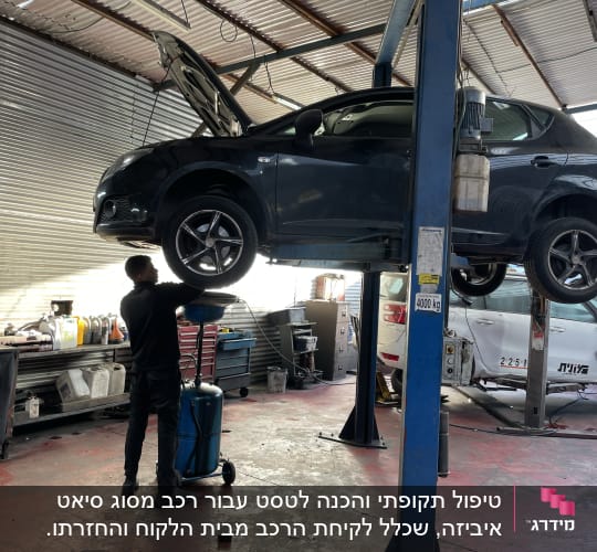 מכונית על ליפט במוסך, מכונאי עובד מתחתיה